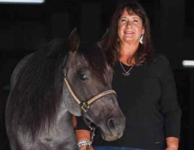 Beverly Servi standing beside a blue roan horse